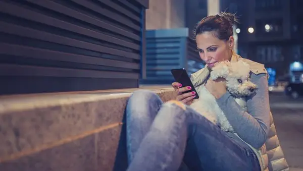 woman on phone in street holding dog