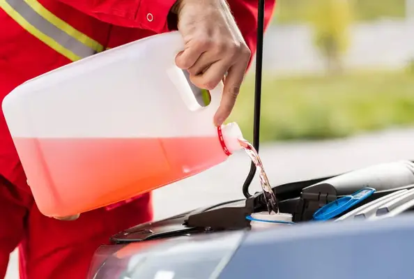 Man pouring antifreeze in the car.