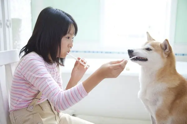 Una mujer cepillándose los dientes con su perro.