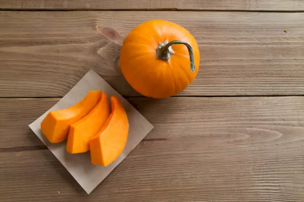 pompoenschijfjes op perkamentpapier en de hele pompoen