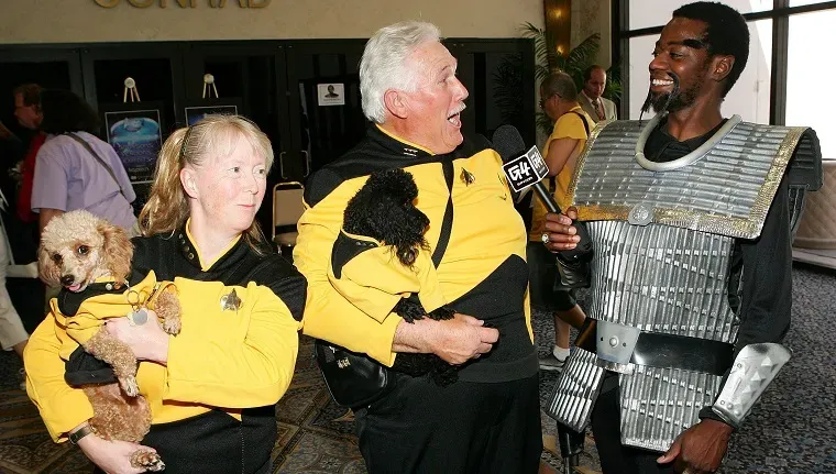 라스베가스 - 8월 17일: 2006년 8월 17일 라스베거스 네바다주 라스베거스 힐튼에서 열린 제5차 연례 공식 스타 트렉 컨벤션에서 캘리포니아의 G4TV 특파원 William O'Neal과 인터뷰하는 동안 캘리포니아 출신의 Pat Krob(왼쪽)과 그녀의 남편 Ken Krob이 Tasha Yar(왼쪽)이라는 이름의 푸들과 Mr. Data를 안고 있습니다.' title=