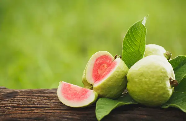 Guava affettata su tavolo di legno con sfondo verde naturale