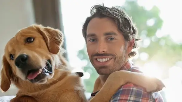 Smiling man petting dog indoors